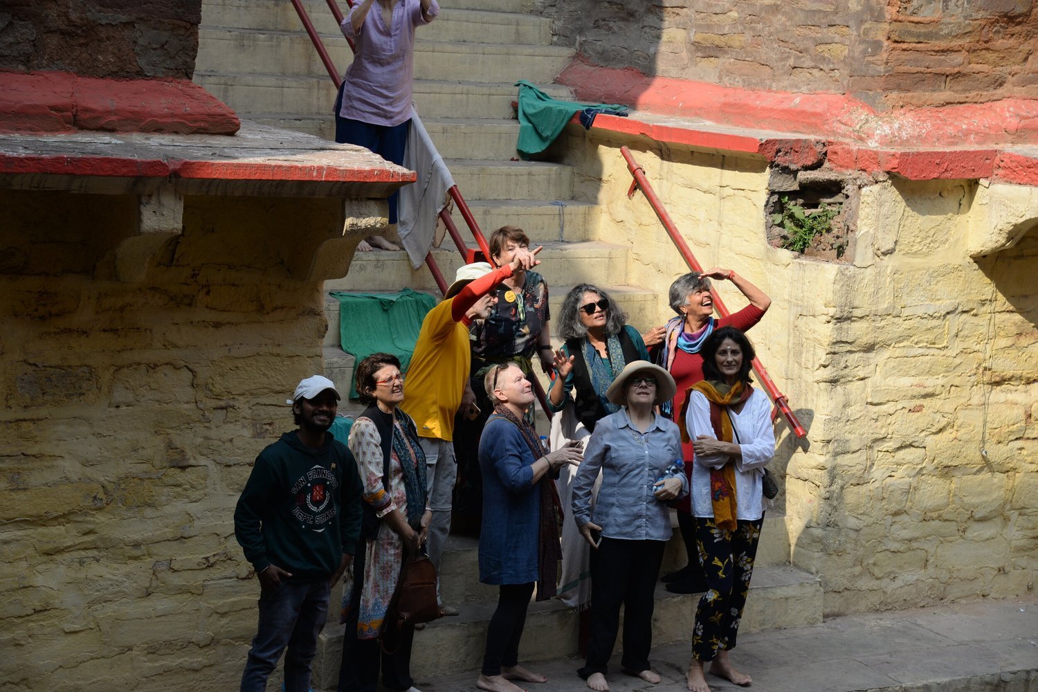 The group looking up from the steps of an ochre stone stepwell